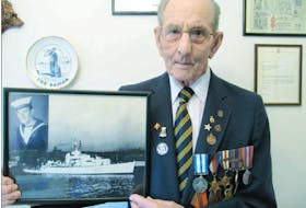 Ralph Patterson, pictured when he was 91, displays a photo of the HMCS Nene, a ship he served on as a leading torpedo operator in the Second World War. Tucked in the upper left corner of the picture frame is his portrait.