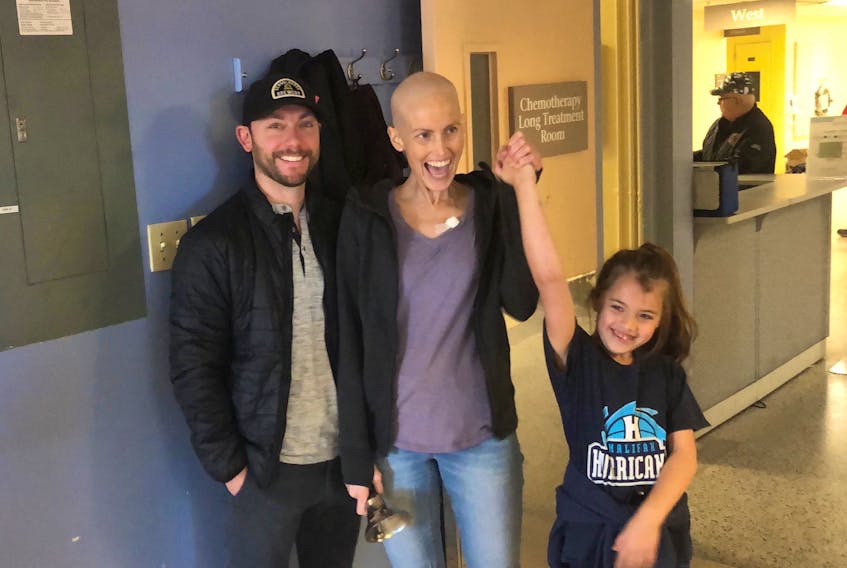 Judy DesRoches celebrates her last chemotherapy treatment by ringing the bell with her husband, Marc, and daughter, Lydia.