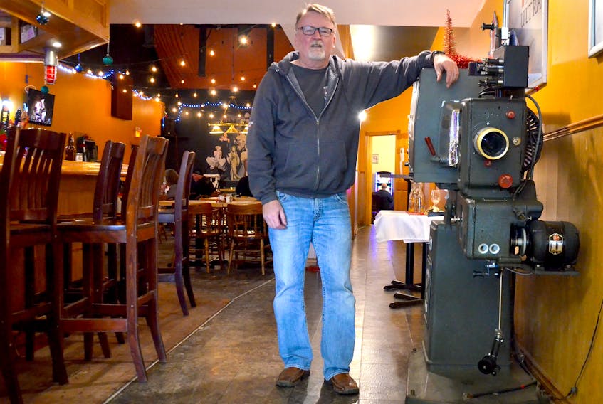 Capitol Pub owner John Bartlett stands beside a movie projector from 1944 that would have been similar to the one used in the Capitol Theatre that opened in 1936 in Middleton. The movie-era relic was given to him by the ZedEx Theatre in Greenwood.