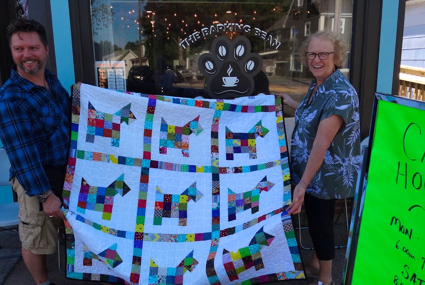 Glenn Deering, owner of the Barking Bean Café, accepts a donated quilt from the Avon River Quilters. Quilting group member Helen Donaldson made the presentation.