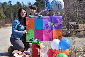Erin Veinot and her daughter Brooklynn collect some surprise gifts left at the end of their driveway by some friends and family who drove by their home shortly after noon March 29 as part of a surprise makeshift parade held to lift the six-year-old’s spirits at a time when important provincial social distancing protocols and gathering restrictions must be followed.