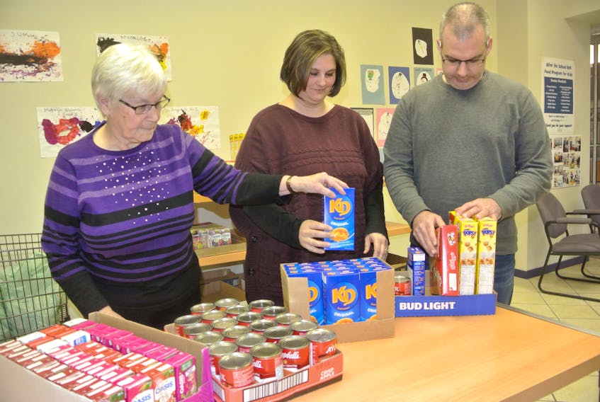 (From left) Volunteers Doris Walton and Shelley and Tim Stevens look over some of the food items for the After the School Bell Food Program that supports students at West Highlands Elementary. The three-month pilot project, which is now full-time, saw 350 food bags sent home with 25 students at the Amherst school on a weekly basis.