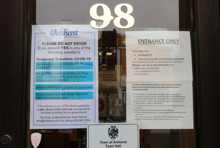 The sign on the left of the front door to Amherst town hall asks people to refrain from entering the building if they have been outside the Atlantic provinces, been exposed to an individual infected by COVID-19, are experiencing COVID-19 symptoms or have any other illness that could infect others. Tom McCoag/Town of Amherst