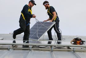 Thermo Dynamics Ltd. crew members intsall one of the 260 solar panels being placed on the roof of the Amherst Stadium as part of the provincial Solar Electricity fo Community Buildings Program. Tom McCoag / Town of Amherst photo