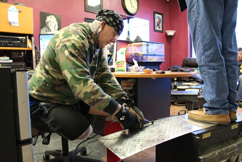 Tattoo artist Artie Gautreau cuts a steel sheet he plans to use during renovations at his shop, Extreme Ink, in Charlottetown. Gautreau lost part of one leg after someone used a vehicle to pin him against the building of his shop on Dec. 23.