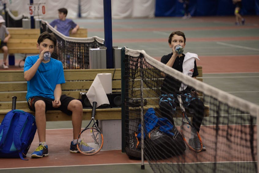 Anthony Shaw of Nova Scotia (left) and Liam Drover-Mattinen of Newfoundland and Labrador rehydrate between sets on Day 1 of the Atlantic indoor tennis championships at the Greenbelt Tennis Club Thursday in St. John’s.