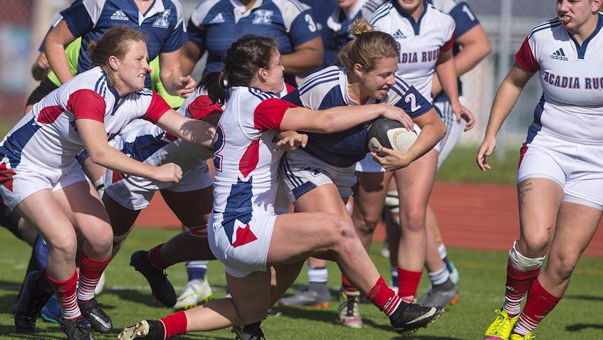 
Acadia Axewomen’s Alysha Corrigan, centre, takes down St. Francis Xavier X-Women’s Danielle Cormier during an AUS women’s rugby game at Raymond Field in Wolfville last Sunday afternoon. The Axewomen host the UPEI Panthers in the AUS semifinal at Raymond Field on Friday evening. - Ryan Taplin
