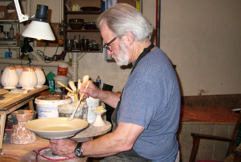 
Tim Worthington, of Birdsall-Worthington Pottery Ltd., applies glaze to a pottery plate. - Lisa J. Ernst
