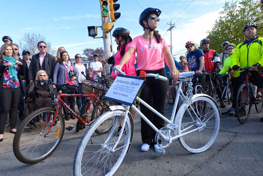 
 Julie Dean stands with the “ghost bike” that was to be left near the scene of an accident that took the life of her twin sister, cyclist Johanna Dean, in Dartmouth in May 2014. Dean, 30, was killed when she slid underneath a delivery truck that ran into her on Windmill Road. FILE

