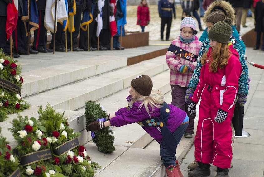 Girls from the Windsor Park Guides place a wreath during the ceremony commemorating the 101st anniversary of the Halifax Explosion on Thursday.