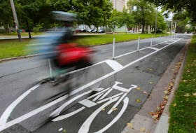 
A cyclist whizzes by in a dedicated bike lane on University Avenue. - File
