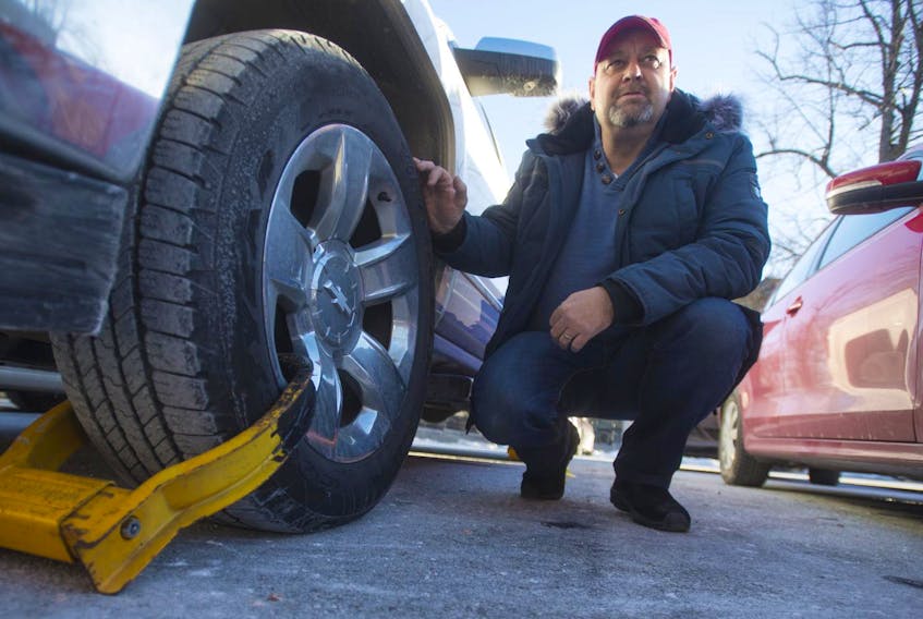 Don White waits to have a boot removed from his pickup truck at a parking lot at the intersection of Spring Garden Road and Grafton Street on Thursday afternoon.