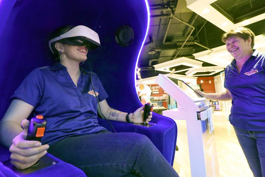 Showroom consultant Megan Baker at the Giant Promotions store in the Sunnyside Mall in Bedford tries out the virtual reality pod as owner Marlene Masad watches.