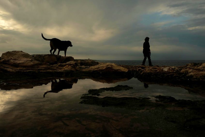 
A woman and her pet dog walk along the coastline at Pembroke, Malta on March 19, 2019. - Reuters

