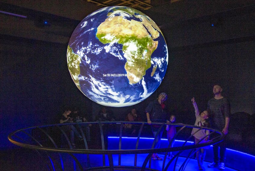 
A family watches the world spin in the global projection display at the Nova Scotia Museum of Natural History in Halifax on Monday, Earth Day. - Tim Krochak 
