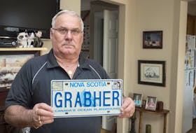 
Lorne Grabher holds his license plate which he is no longer allowed to have on his car because of the spelling of his last name. - File
