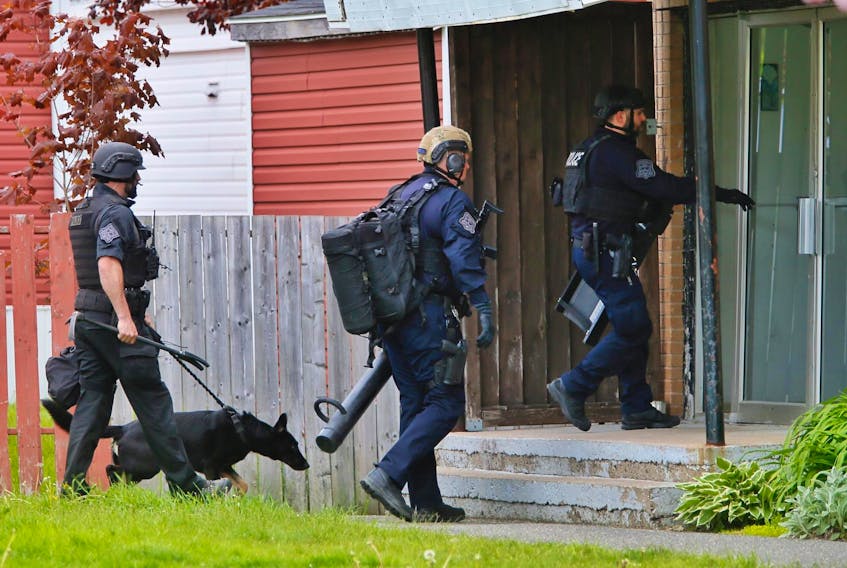 
HRP officers, including a dog handler, enter a Forbes Street apartment building in Halifax on Tuesday. 
