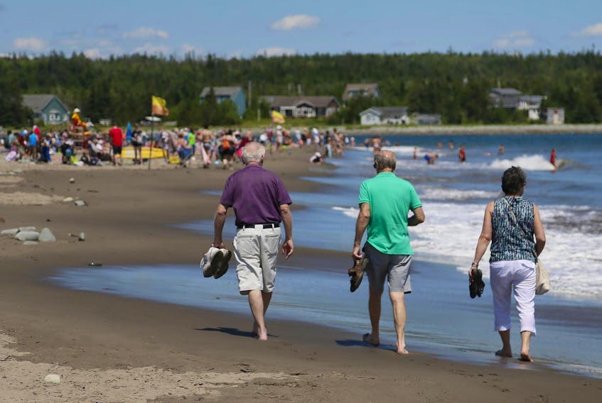 Beachgoers cool off as they walk along Rainbow Haven Beach on another warm summer’s day on Tuesday.
