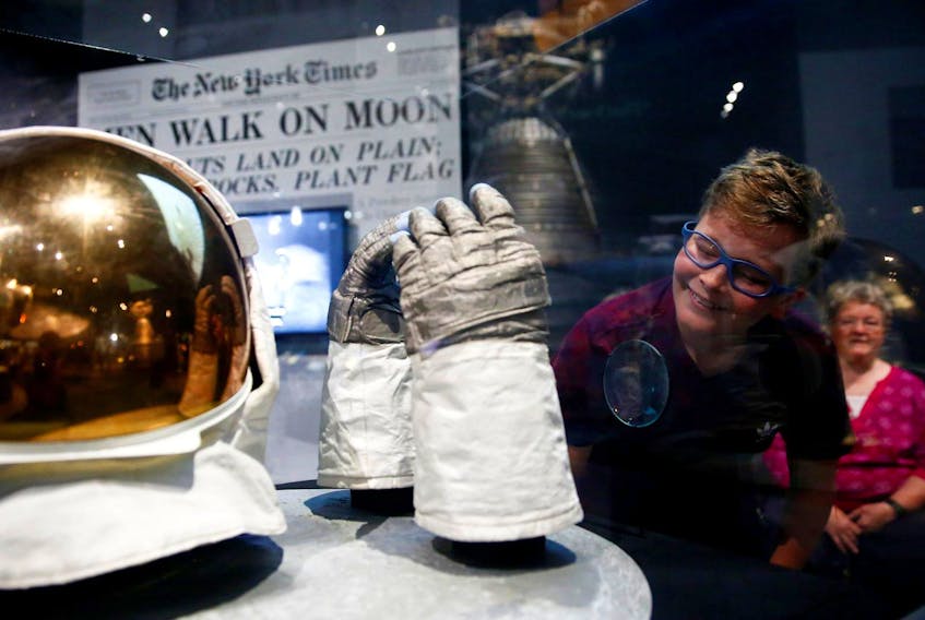 
Dane Hartmann of Portland looks at Buzz Aldrin’s extra-vehicular gloves at the Destination Moon: The Apollo 11 Mission exhibit at the Museum of Flight in Seattle, Wash. on Friday. - Reuters
