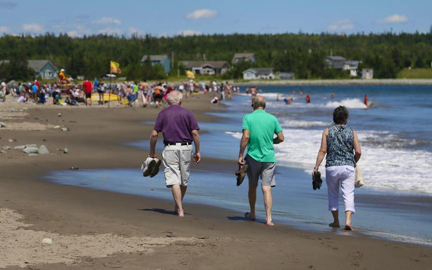 
Beachgoers cool off as they walk along Rainbow Haven beach on a warm summer day. - File

