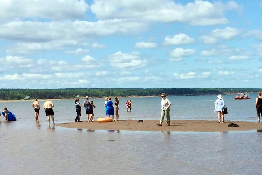 
People stand on a sand bar at Blue Sea Beach after a pair of five-year-old girls were brought ashore by members of the Wallace Fire Department. The pair were on two floaties that were blown offshore by the wind. - Lisa Betts
