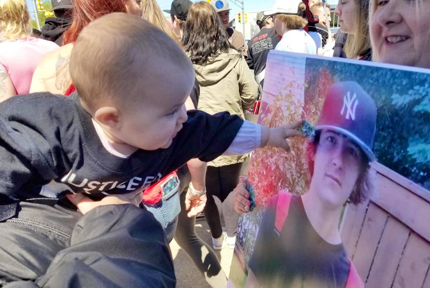 Joneil Hanna’s infant daughter, Harper, is shown reaching for her late father’s portrait during a Justice for Joneil rally at the Cape Breton Regional Police detachment in Sydney Mines on June 16, 2018.
