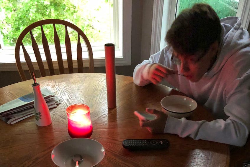 A 17-year-old Dartmouth resident eats by candlelight in the aftermath of Dorian.