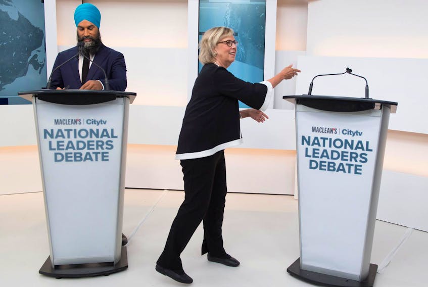 
Green Party leader Elizabeth May reaches to the empty mic stand where the invited Liberal leader and Prime Minister Justin Trudeau turned down an invitation to the Maclean's/Citytv National Leaders Debate, next to New Democratic Party (NDP) leader Jagmeet Singh on the second day of the election campaign in Toronto, Ontario, Canada September 12, 2019. - Frank Gunn/Pool via REUTERS
