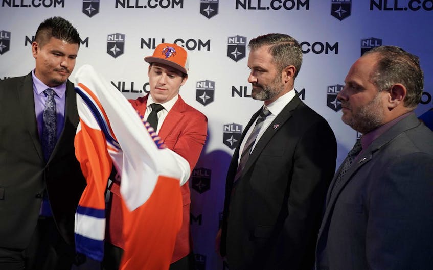  Clarke Petterson puts on his uniform after being drafted five overall by the Halifax Thunderbirds in the Narional Lacrosse League draft on Tuesday night in Philadelphia. From left are: Brandon Styres, Clarke, head coach Mike Accursi and president and CEO John Catalano