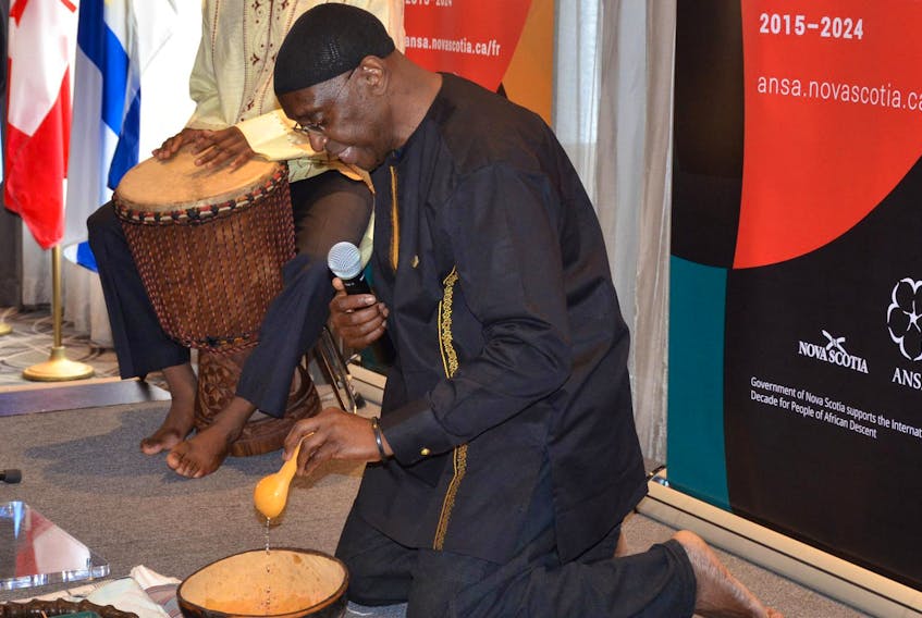 Wayn Hamilton, executive director of African Nova Scotian Affairs, pours a mixture of water from Beechville and Ghana at a libation ceremony Thursday to kick off the province’s Count Us In action plan in response to the International Decade for People of African Descent, while his son, Khalifa Jallo-Hamilton, plays a drum.