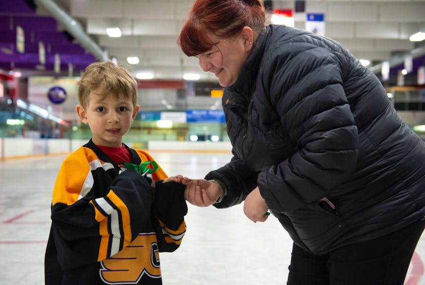 Jerri-Lynn Dubeau assists her son Brayden, 5, to put on a Gander Flyers jersey and a green ribbon for a tribute ceremony to the Humboldt Broncos April 10 at the Steele Community Centre. Sixteen people lost their lives in a tragic bus accident as the team was travelling to a game in Nipawin, Saskatchewan April 6.
