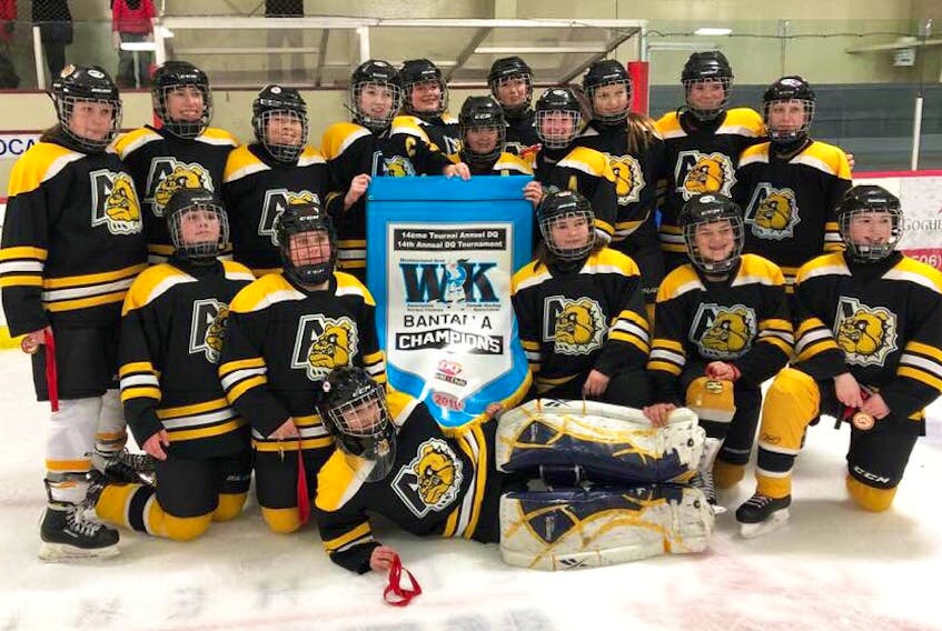 The Antigonish Bantam ‘A’ female Bulldogs celebrate their Dairy Queen Female Hockey Tournament title with the championship banner and gold medals.