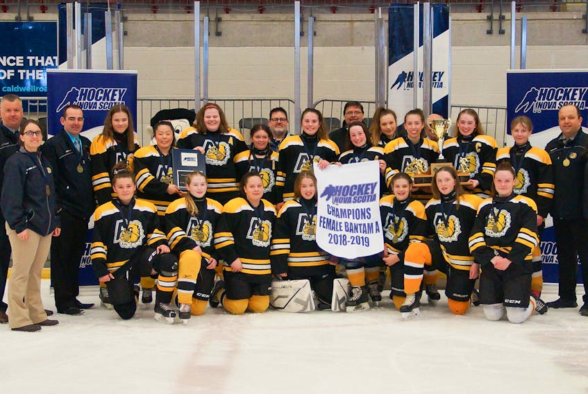 The Bantam ‘A’ female Bulldogs gather with their provincial championship banner, plaque and trophy following the Day of Champions final game which they won 5-0 versus Western Riptide White.
