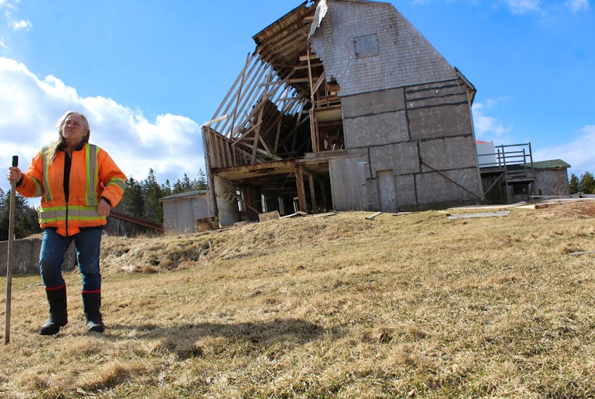 Clara Gray stands in the forefront of her massive hay barn in South Bar that was heavily damaged by high winds on Wednesday evening. Throughout its history the barn, estimated to be 100 years, had successfully withstood many big storms.