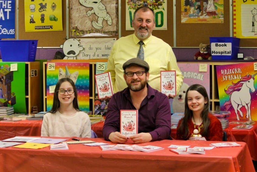 Darrell Duke, his daughters and illustrators Emma and Jessica, and Riverside principal Peter Hackett with the book "Crunch and Munch: Volume 1." CONTRIBUTED