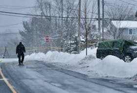 A Halifax Regional Police officer walks past evidence markers placed on Mount Edward Road in Dartmouth after a shooting Saturday. A man driving a vehicle that crashed into a utility pole suffered life-threatening injuries in the shooting.