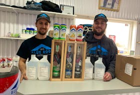 Blue Roof Distillers CEO and founder Devon Strang (left) and head distiller Cameron Boyd look over some of the company’s award-winning spirits, including vodka and gin, as well as its newest product, hand sanitizer.