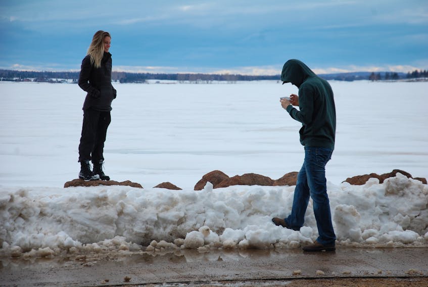Shawn MacArthur checks his digital photography work after snapping a few photos of Jessie Campbell on Monday along the boardwalk in Charlottetown. The Cornwall couple was enjoying a stroll as rain and above zero temperatures started eating away at the snow.