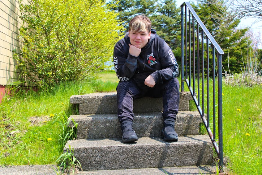 Brett Corbett, 15, sits on the steps of his home in Reserve Mines in June. The Glace Bay High School student and his mother have settled their human rights complaint against the Cape Breton Regional-Victoria Centre for Education. The complaint was filed after the family was dissatisfied by the way school administration handled an incident where Corbett was bullied into lying into a stream during a lunch break in October. NIKKI SULLIVAN/CAPE BRETON POST