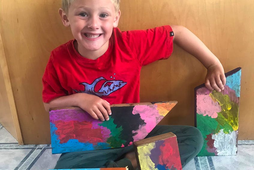 Five-year-old Brooks Chase of West Amherst sits with a painting he created. He made the painting from scrap wood and auctioned it off in support of the After the School Bell Food Program.