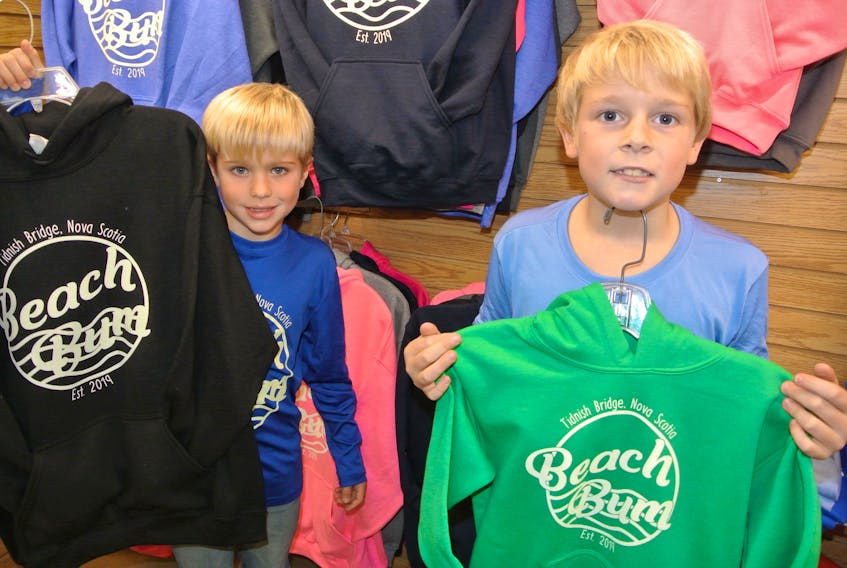 Cole Davis-MacIvor (left) and Oliver MacIvor are the brains behind a new clothing line that’s now being sold at Amherst’s Maritime Mosaic inside Dayle’s Grand Market. The eight-year-old Tidnish Bridge boys came up with the clothing idea as a way to raise money to go to Walt Disney World in Florida. From a small beginning out of their home, they are now shipping product across Canada.