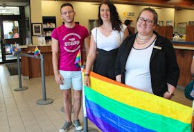 Pride Cape Breton communication director B.J. Singleton and Sydney Credit Union representatives Jennifer Griffin and Adrienne Collins, pose with the Pride flag inside their main branch, located on Townsend Street in Sydney. The bank is opening is helping Pride Cape Breton make the parade on August 3 more inclusive for people with sensory issues, anxiety and mobility issues. Inside will be the Autism Safe Zone, with dimmed lights and low sound.