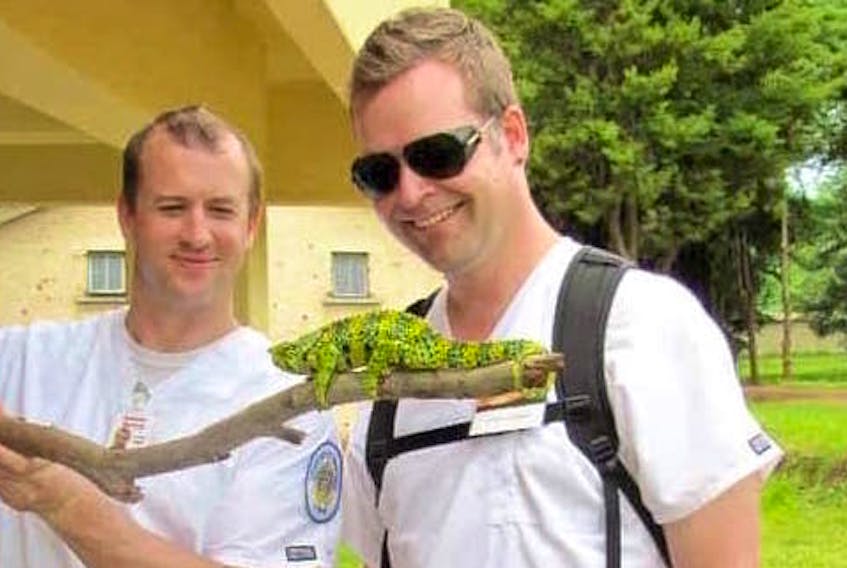 Andy Bunn, left, and a colleague pose with a chameleon in this 2012 taken while Bunn was working in Africa at the Zomba Psychiatric Hospital near Zomba, Malawi. Bunn and his dog are safely back in the U.S. after his 11-metre sailboat crashed into the rocky coastline of Cape Breton of Gabarus last week. However, the Iraq War veteran says his problems began a month early when a Marine Atlantic ferry damaged his boat, and Canada Border Services Agency threatened him with deportation.