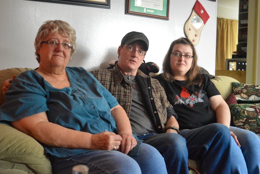 Shannon MacLeod, centre, sits in his childhood home in Glace Bay beside his mother, Georgette MacLeod, left, and his sister, Krista MacLeod. His family worries about Shannon because he has a disorder that affects the spinal cord, causing intense pain every day and he is unable to find a family doctor. Nikki Sullivan/Cape Breton Post