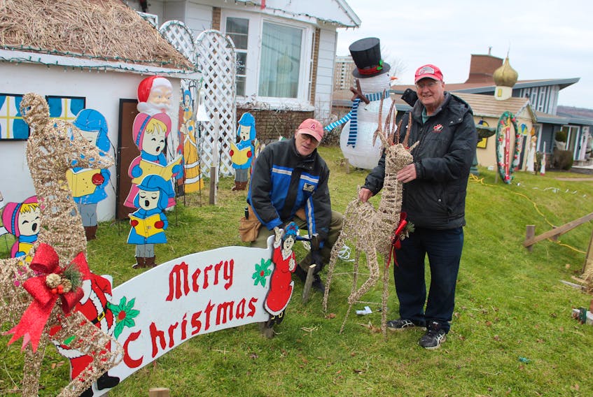 Peter Mombourquette, right, works on setting up his outdoor Christmas display at his Sydney home on Monday with the help of his "elf" Ray Oake.
