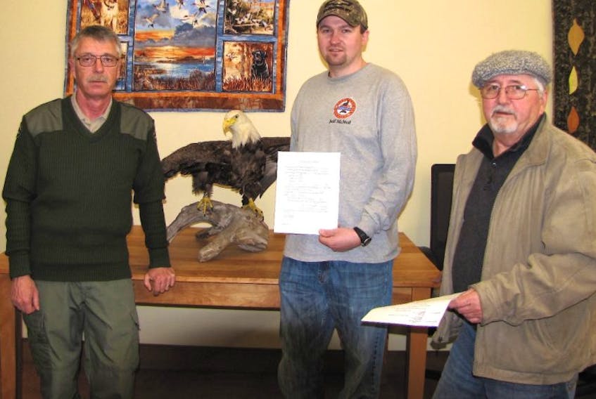 Andy Pyke, from left, a wildlife technician with the Department of Natural Resources, and members of the Port Morien Wildlife Association Jeff MacNeil and Stan Peach get paperwork for an eagle carcass given to the association to have mounted by a taxidermist for educational purposes. The association says they will be custodians of the eagle but it will still legally belong to the Department of Natural Resources.