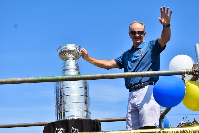 Al MacInnis waves to the crowd as he holds the Stanley Cup during the annual Chestico Days parade in Port Hood on Saturday. MacInnis, who won the NHL championship with the St. Louis Blues as a senior advisor, celebrated the Stanley Cup win in his home community.