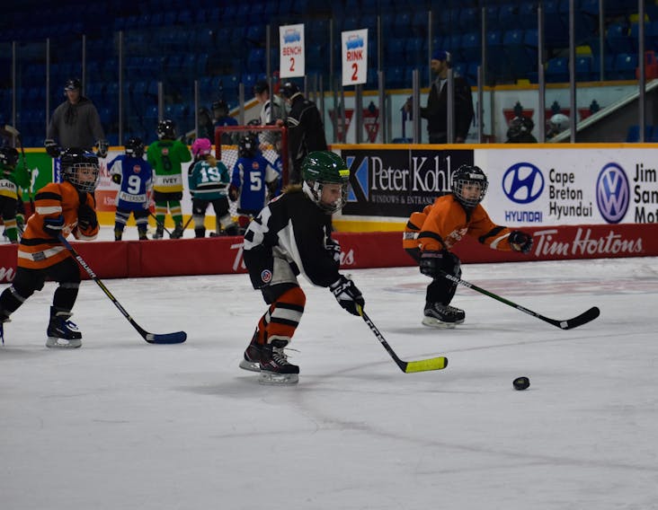 Six-year-old Leland MacDonald, in black, breaks away with the puck in hopes of scoring a goal during the Tim Hortons Timbits Jamboree on Sunday at Centre 200.