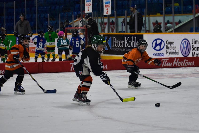 Six-year-old Leland MacDonald, in black, breaks away with the puck in hopes of scoring a goal during the Tim Hortons Timbits Jamboree on Sunday at Centre 200.