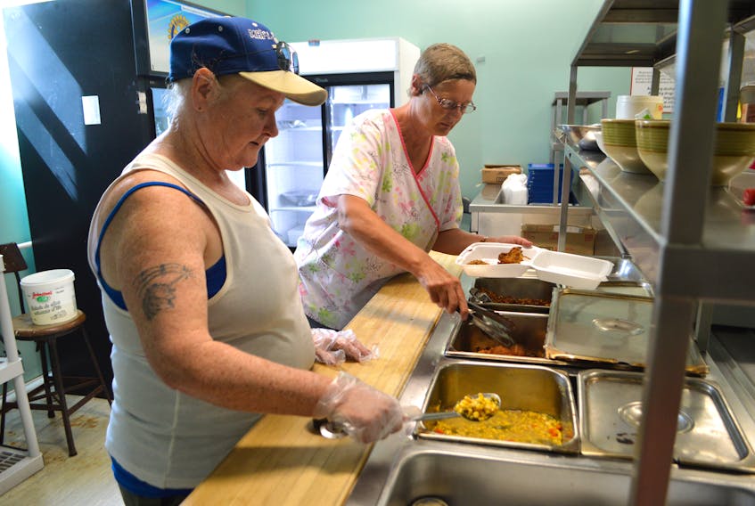 Florence MacNeil of New Victoria, left, a volunteer at Loaves and Fishes, and Marguerite MacDonald of Sydney, culinary supervisory, prepare takeout meals on Tuesday at the Sydney facility. Manager Marco Amiti said despite the COVID-19 pandemic, Loaves and Fishes has managed to stay open and is serving on average 100 individuals a day, about half the number of meals served before the pandemic.